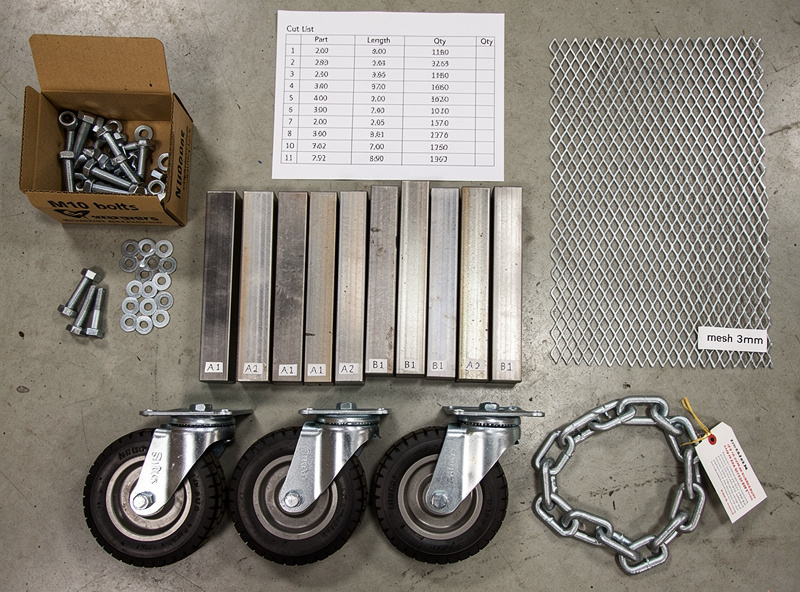 Top-down view of welding cart materials laid out on a workshop floor showing square steel tubing in different lengths cut to size with cut list, expanded metal mesh, four caster wheels, chain, hex bolts and washers