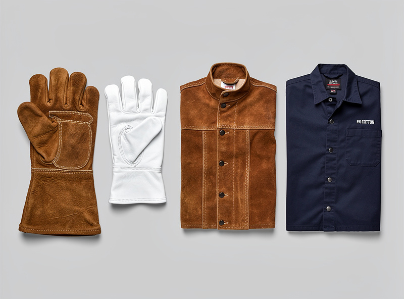 Photograph showing three types of welding upper-body protection on a rack: a heavy leather welding jacket, an FR cotton jacket, and a leather apron