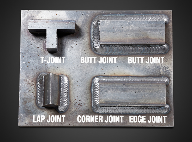 Close-up photograph of a T-joint on mild steel angle iron showing the fillet weld bead in the inside corner with proper 45-degree work angle and consistent penetration into both legs