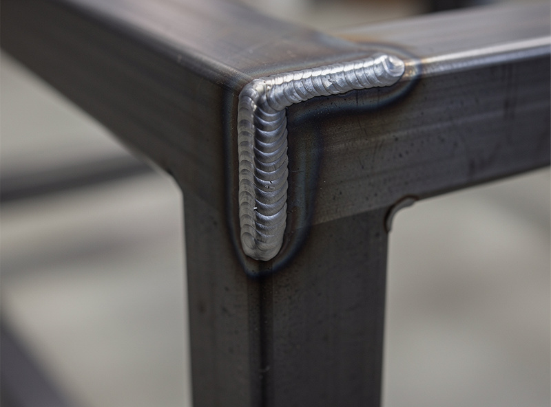 Detailed close-up of a fillet weld at the corner of two square steel tubes