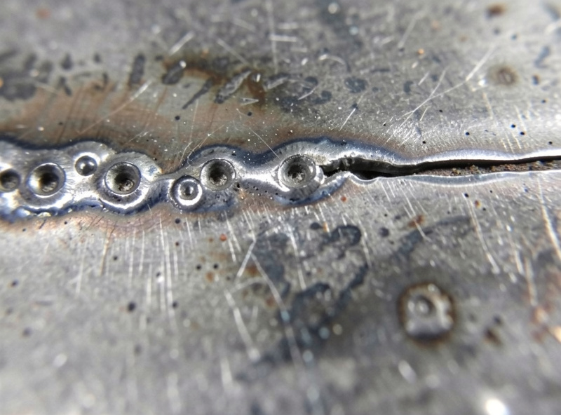 Macro of a broken weld fracture face showing gas porosity and an unfused boundary