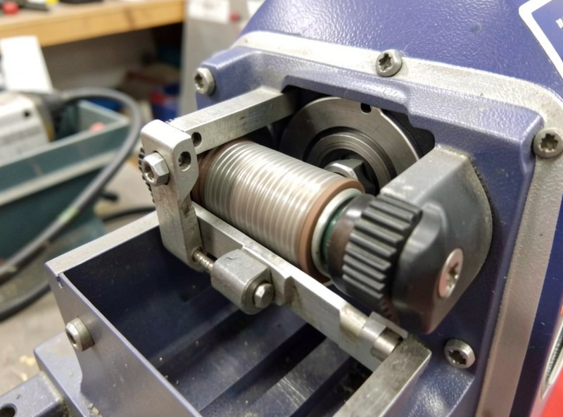 Close-up of MIG welder drive roll and tension knob inside the wire feed mechanism