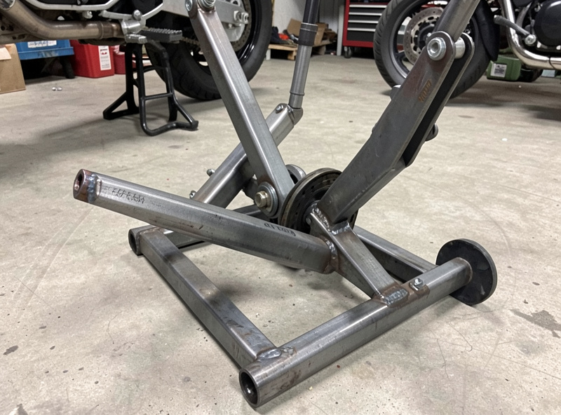 Welded square tube motorcycle swingarm maintenance stand holding a bike's rear wheel off the ground