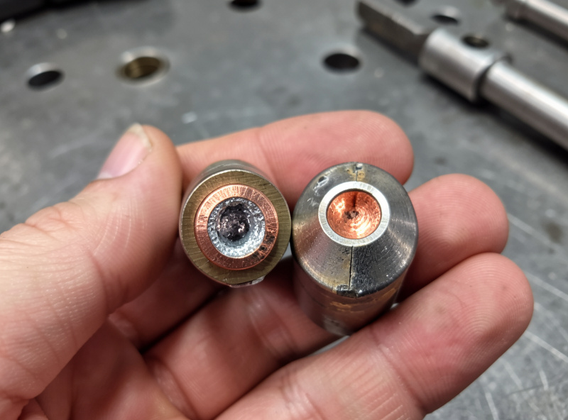 A used plasma electrode with a pitted hafnium center next to a fresh electrode for comparison