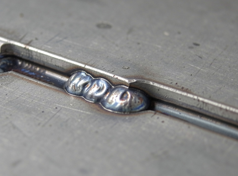 Macro view of an undercut groove melted into the base metal beside a steel weld bead