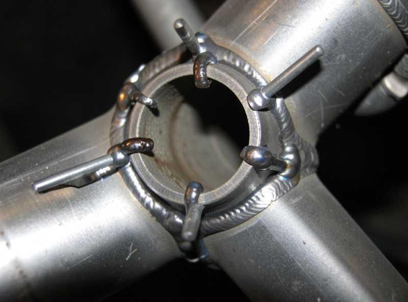 Spaced tack welds around a circular exhaust pipe joint showing skip welding pattern
