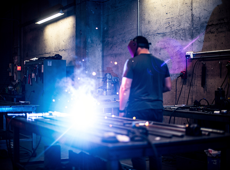 Bright welding arc light reflecting off shop walls toward a bystander standing too close