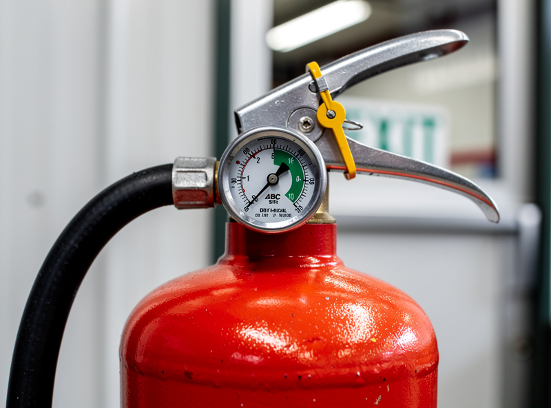 ABC dry chemical fire extinguisher mounted at hand height near a workshop exit
