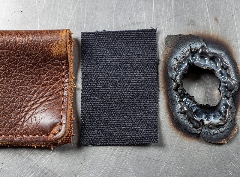 Fabric swatches compared: leather, FR cotton, and melted synthetic with a burn hole