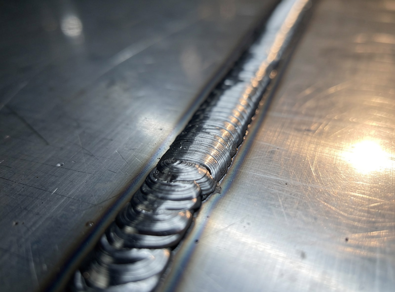 Aluminum MIG bead being run with a spool gun showing a bright wide weld on aluminum plate