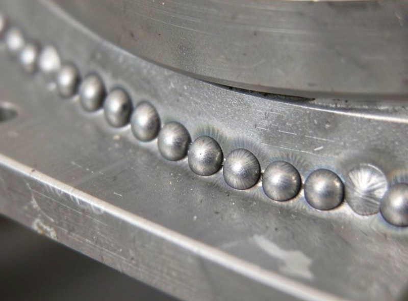Row of plug welds along an overlapping car panel flange copying factory spot welds