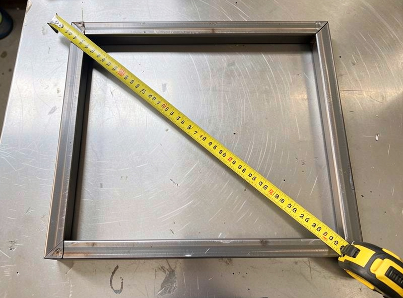 Tape measure across the diagonal of a steel tube frame to check it is square