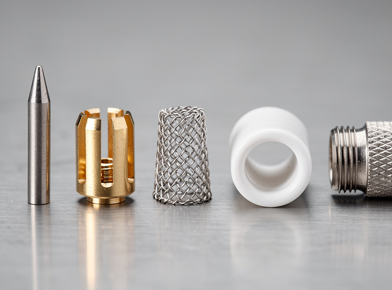 Disassembled TIG torch consumables laid out in order: tungsten, collet, gas lens, alumina cup, and back cap