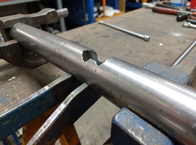 A fishmouth-notched tube dry-fitted against its mating tube with no visible gap, held in clamps on a welding table