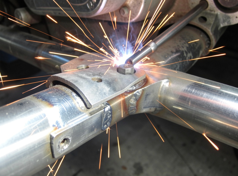 Grinding a muffler hanger bracket and exhaust pipe back to bright metal before welding