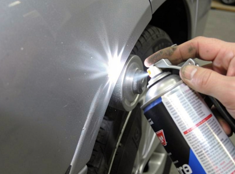Spraying weld-through primer onto the mating flange of a car panel before welding