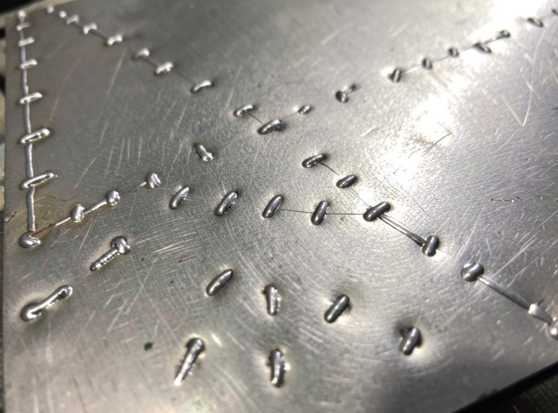 Close-up of stitch welding a thin sheet metal patch with spaced tack welds