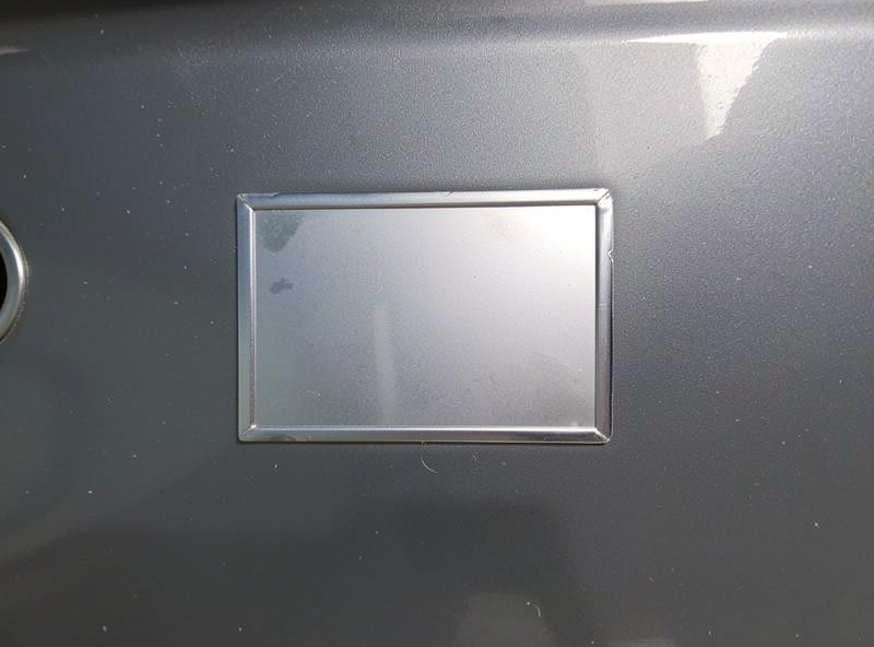 A cut sheet metal patch fitted into a rust repair opening on a car body panel