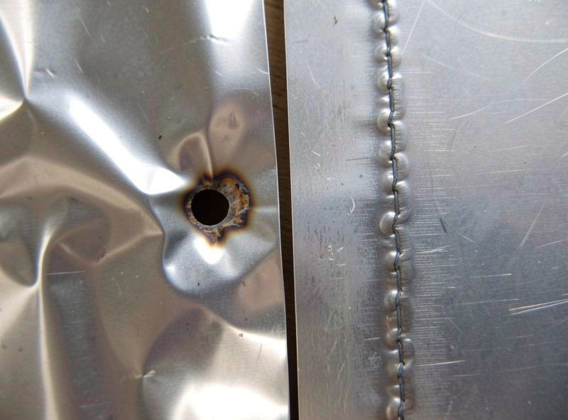 Warped thin aluminum sheet with a burn-through hole next to a clean stitched weld on another sheet