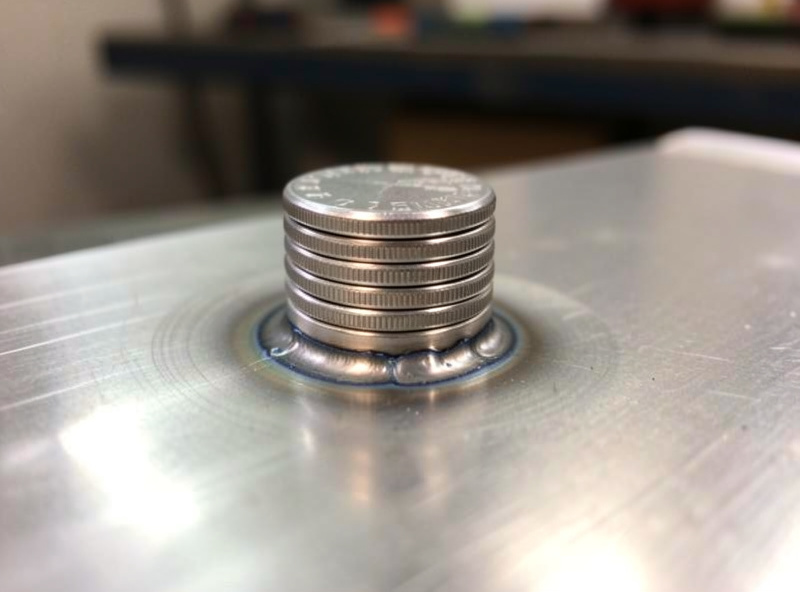 Close-up of a stacked-dime aluminum MIG weld bead on a bright aluminum plate