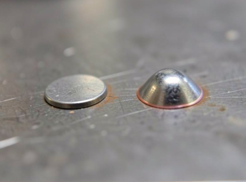 Two MIG weld beads side by side on a steel plate, one flatter and one more crowned