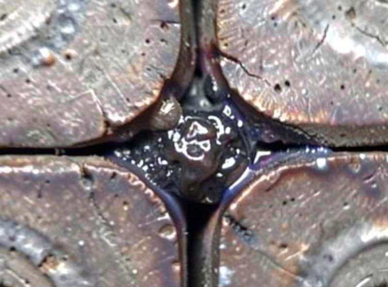 Close-up of a flux-core weld cross-section showing a dark slag inclusion trapped between passes