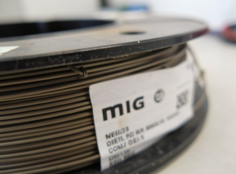 Close-up of a partly used spool of MIG wire showing remaining wire and the weight label