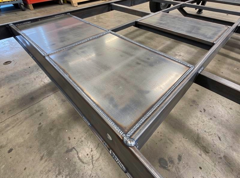 Welded steel sheet decking on a trailer frame with stitch welds along the crossmembers