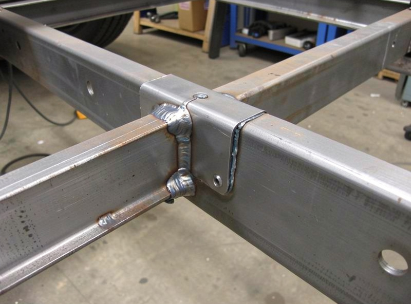 A steel fishplate reinforcement welded over a repaired section of a trailer frame rail